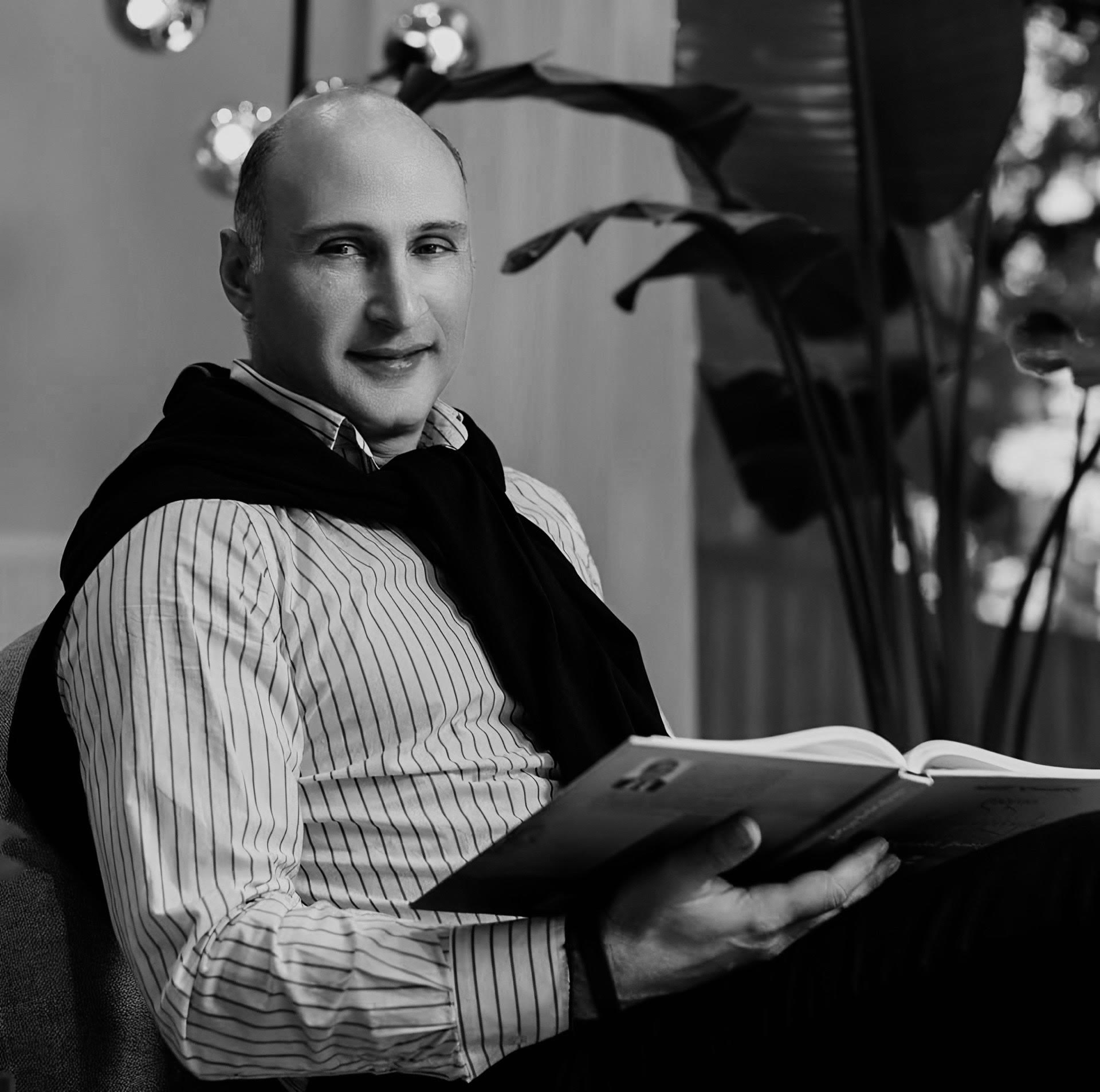 George Goguadze, Georgian banker, entrepreneur, and Doctor of Economics, founder of UNIC Water Project, seated with a book in a modern interior setting.